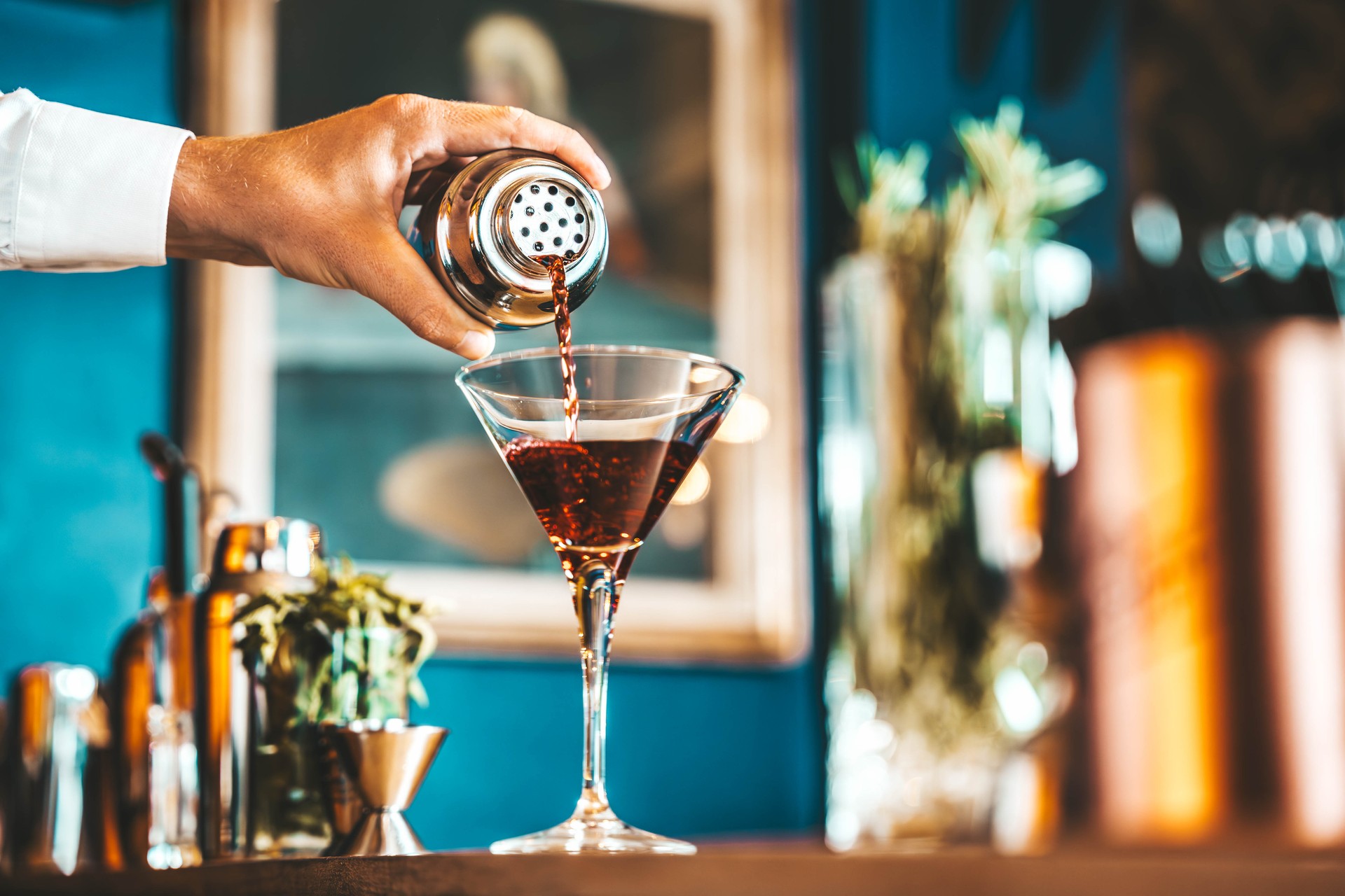 Bartender pouring alcohol into the glass at cocktail lounge bar venue in hotel lobby  - Focus on manhattan cocktail