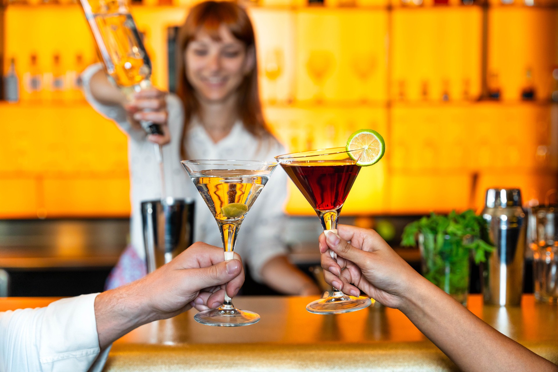 Bartender pouring alcohol from the bottle into the glasses at cocktail lounge bar venue in hotel lobby - Life style concept with barman making drinks and serves customers