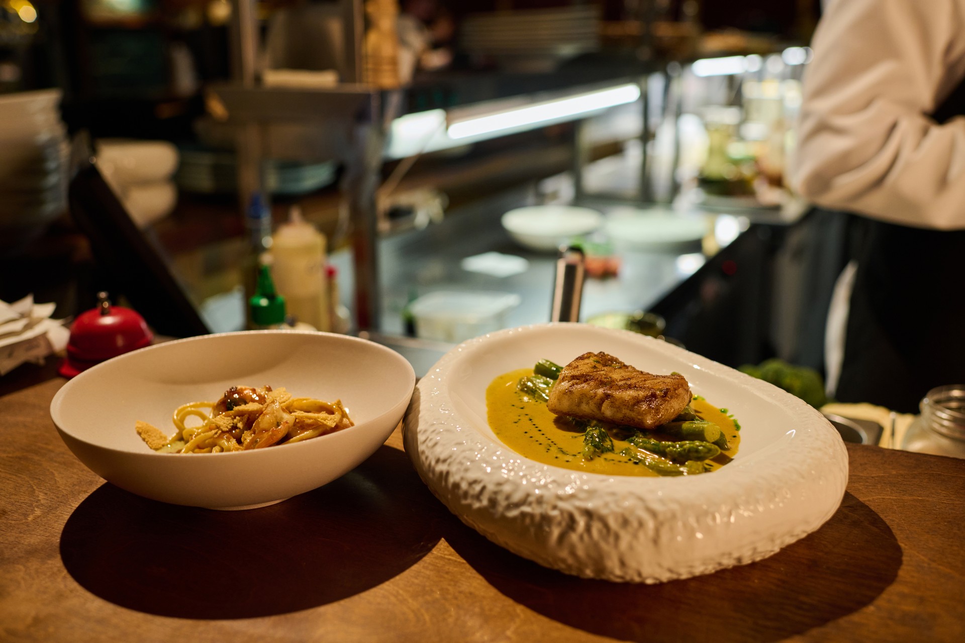 Plate with roasted fish fillet with green beans and sauce and bowl with pasta